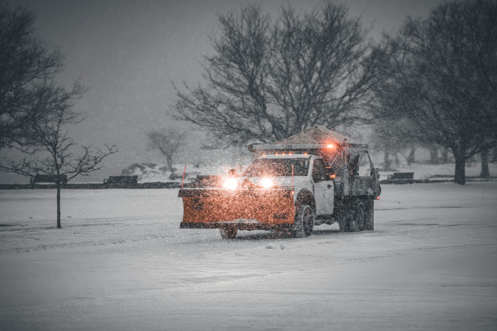 Commercial snow plow clearing a property during snowfall